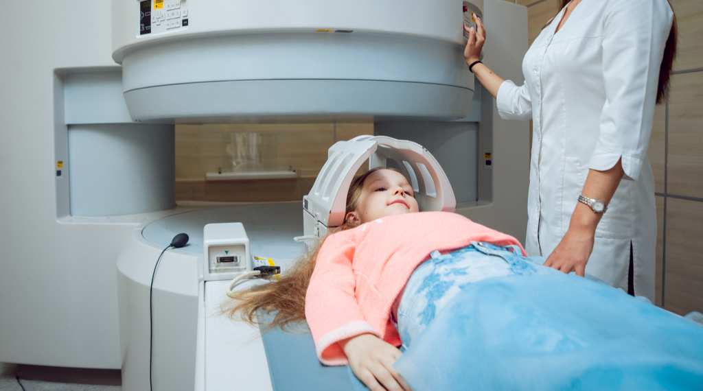 Young girl in a pink shirt getting ready to go in an MRI machine