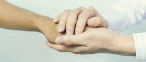 Gentle hands holding a patient hand